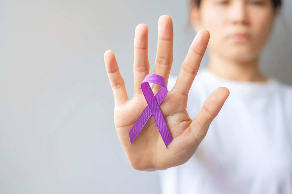 Hand holding up purple ribbon