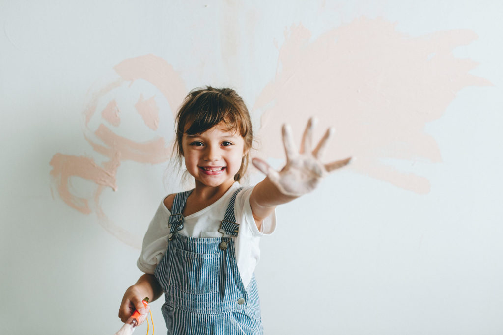 Child doing painting on white wall