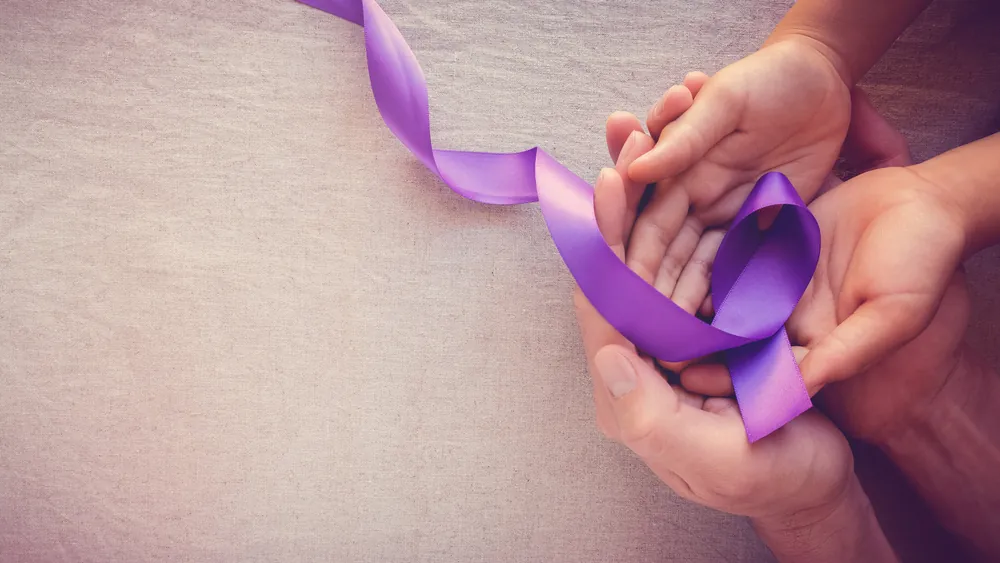 Hands holding a purple domestic violence awareness ribbon, representing safety, support, and legal protection.