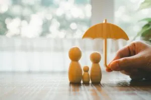 Parent and child model holding an umbrella on a wooden table.