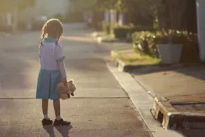 5 year old little girl stand alone at the street lonely with her doll.