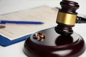 Marriage contract, golden wedding rings and gavel on white background.