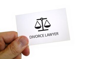 The fingers of a man holding a divorce lawyer card.