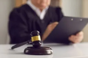 Brown judge's gavel on the table against the background of a judge reading the divorce verdict.