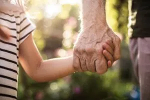 Child hand holding his elderly grandfather