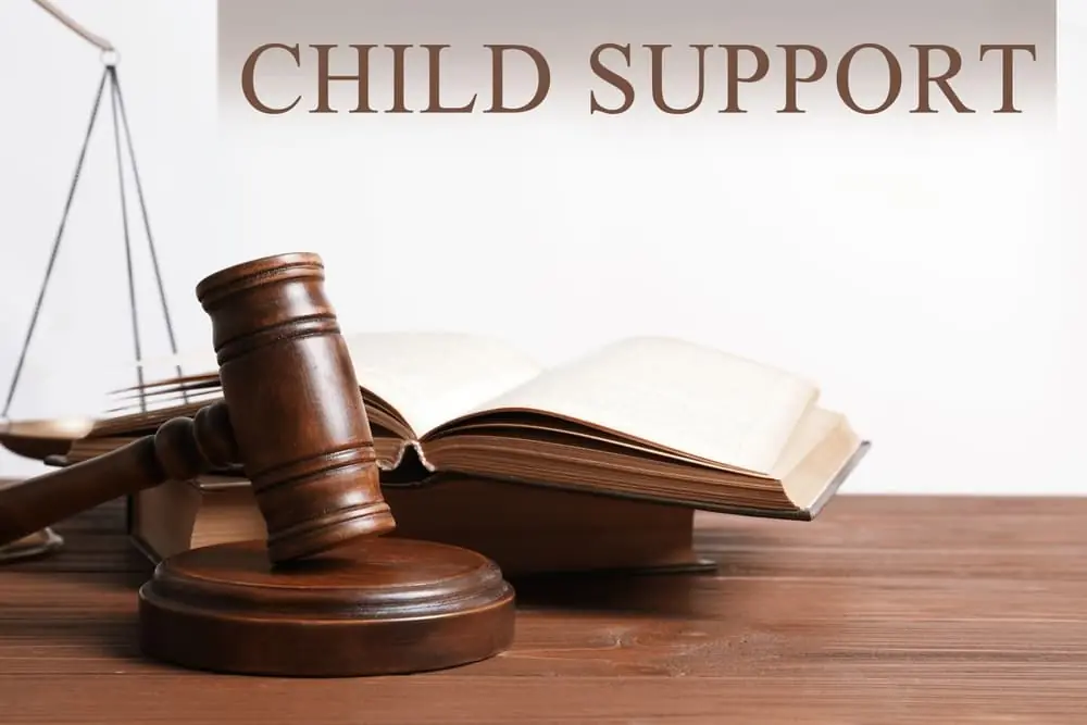 Judge's gavel with scales of justice and law books on wooden table symbolizing child support and family law.