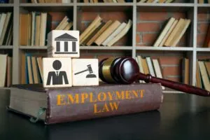 Employment law book with wooden cubes and a judge’s gavel symbolizing workplace regulations and legal compliance