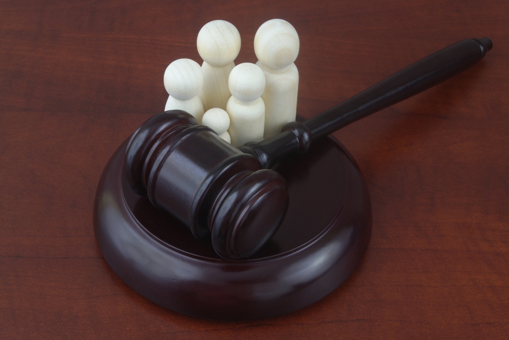 Wooden family figures next to a judge’s gavel on a desk