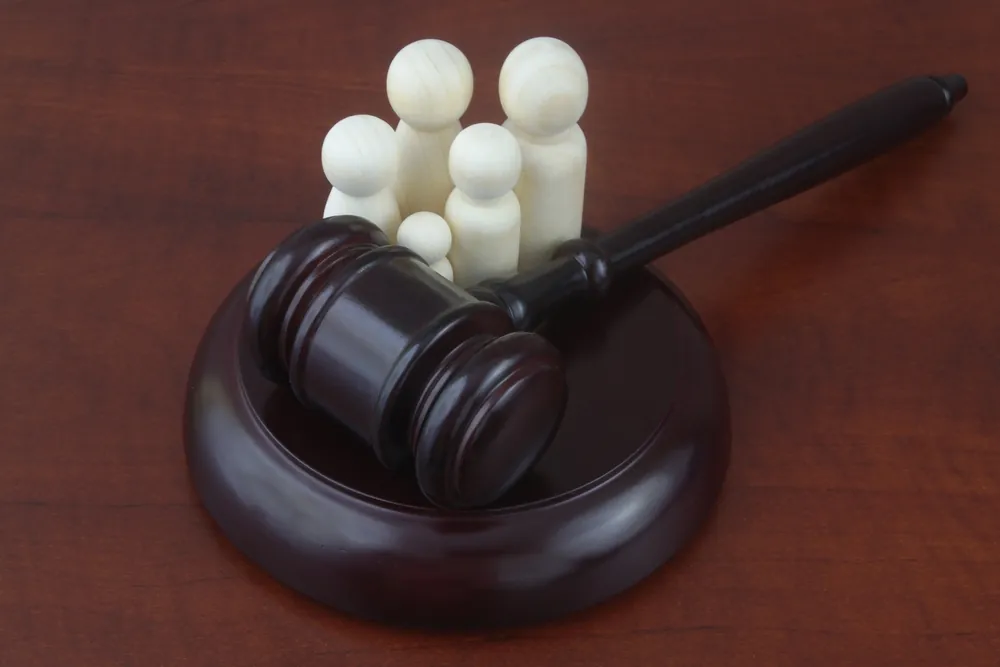 Wooden family figures next to a judge’s gavel on a desk