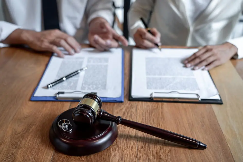 Close-up of couple's hands signing documents related to a divorce